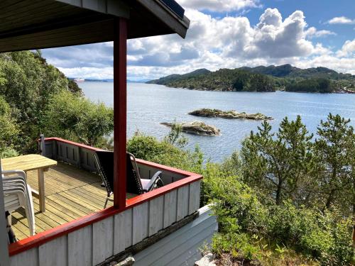 a house with a deck with a view of a lake at Bergen/Sotra:Waterfront cabin(s).Boat.Fish.Jacuzzi in Haganes