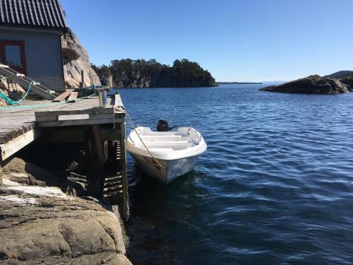 a boat is docked at a dock in the water at Bergen/Sotra:Waterfront cabin(s).Boat.Fish.Jacuzzi in Haganes