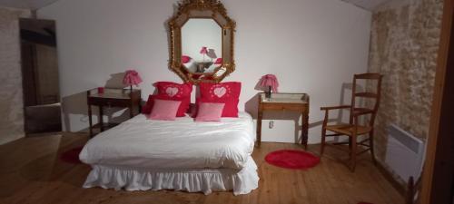 a bedroom with a bed with red pillows and a mirror at Gîte Rouge Calme et Nature in Allas-Bocage