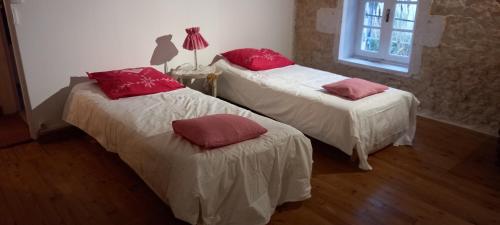 two beds in a room with red pillows on them at Gîte Rouge Calme et Nature in Allas-Bocage