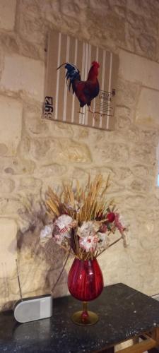 a red vase with flowers in it on a table at Gîte Rouge Calme et Nature in Allas-Bocage
