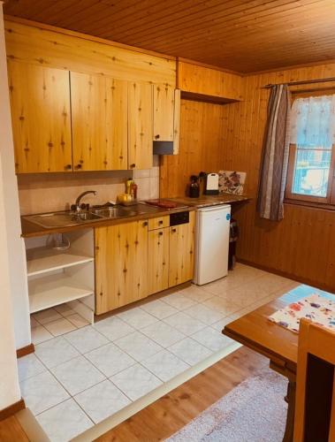 uma cozinha com armários de madeira e um frigorífico branco em Günstig und Einfaches Studio auf dem Bauernhof em Zuoz