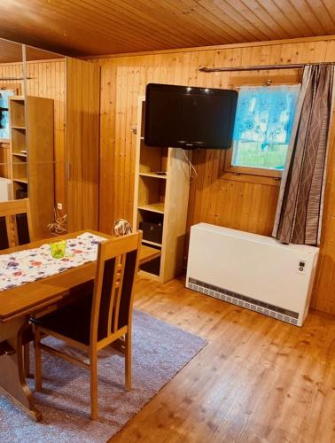 ein Esszimmer mit einem Tisch und einem Flachbild-TV in der Unterkunft Günstig und Einfaches Studio auf dem Bauernhof in Zuoz
