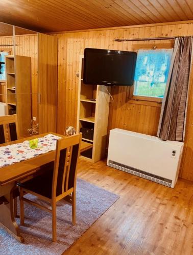 a dining room with a table and a flat screen tv at Günstig und Einfaches Studio auf dem Bauernhof in Zuoz