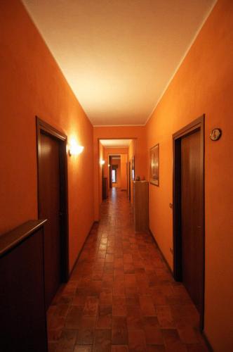 a hallway with orange walls and a tile floor at Hotel Il Granaio in Porto Mantovano