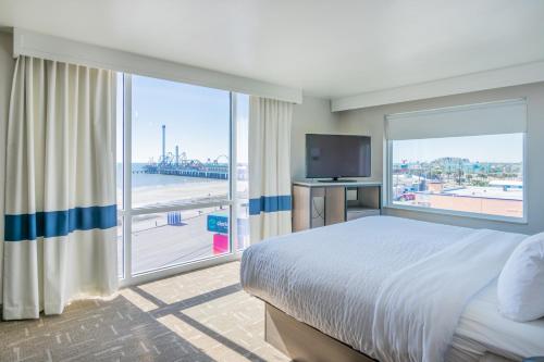 a bedroom with a large bed and a large window at Clarion Pointe Galveston Seawall in Galveston