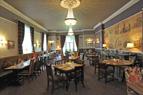 a restaurant with tables and chairs and a chandelier at Royal Hotel by Greene King Inns in Ross on Wye