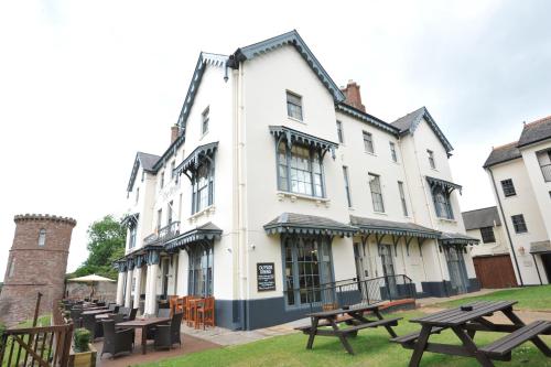 a white building with picnic tables in front of it at Royal Hotel by Greene King Inns in Ross on Wye