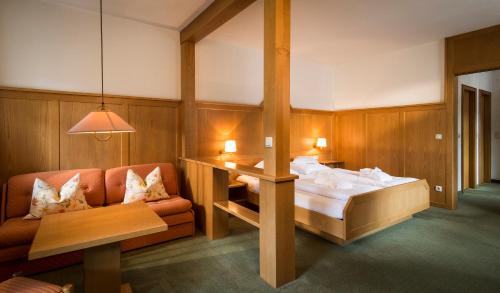 a bedroom with a bed and a couch and a table at Posthotel Rössle in Gaschurn