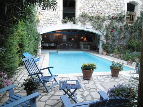 a swimming pool with blue chairs and a table at Le Clos d'Isabelle in Marsillargues