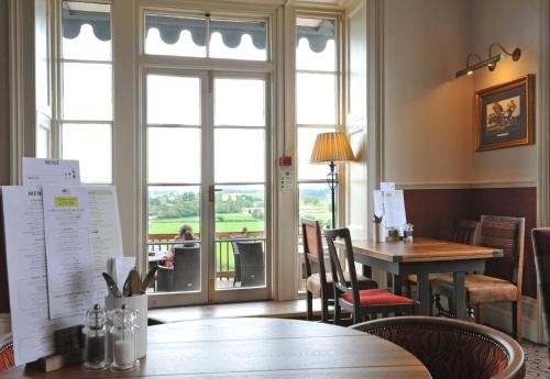 a dining room with a table and chairs and a window at Royal Hotel by Greene King Inns in Ross on Wye