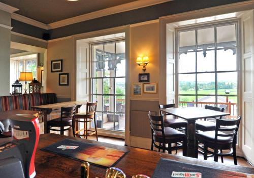 a restaurant with tables and chairs and windows at Royal Hotel by Greene King Inns in Ross on Wye