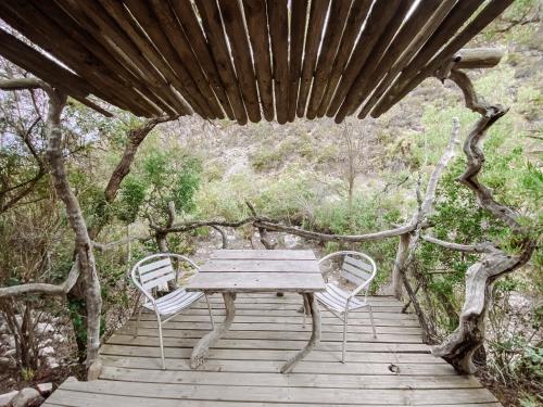 a wooden table and chairs on a wooden boardwalk at Kleinrivier Mountain Escapes in Uitenhage