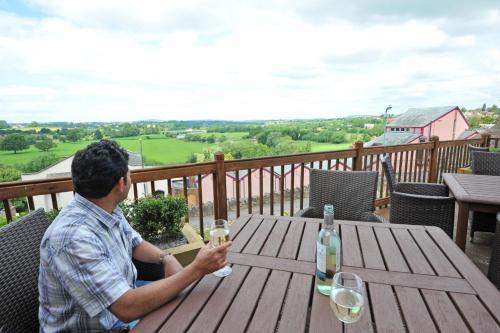 a man sitting at a wooden table with wine glasses at Royal Hotel by Greene King Inns in Ross on Wye