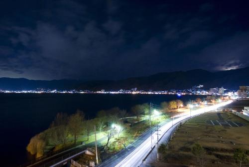 a city at night with lights on the water at Rako Hananoi Hotel in Suwa