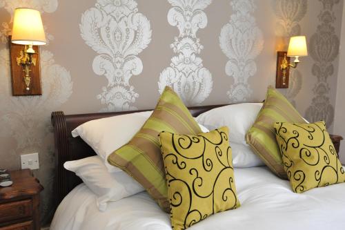 a bedroom with a bed with white sheets and yellow pillows at Royal Hotel by Greene King Inns in Ross on Wye