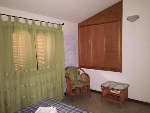 Habitación con cama, silla y ventana en Trilocale Centro Storico - Santa Teresa Gallura, en Santa Teresa Gallura