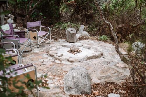 a stone patio with chairs and a fire pit at Kleinrivier Mountain Escapes in Uitenhage