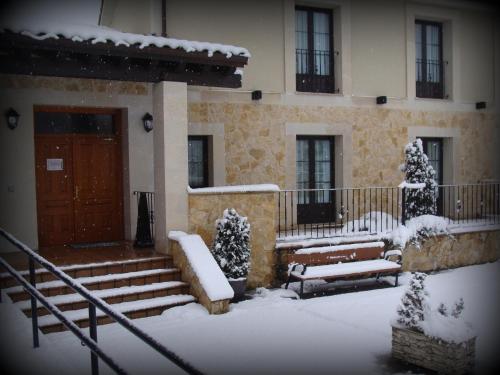 a building with snow covered steps and a door at Alojamiento Rural La Henera in San Juan de Ortega
