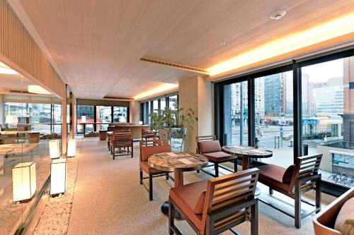a restaurant with tables and chairs and large windows at Hotel COZZI Zhongxiao Taipei in Taipei