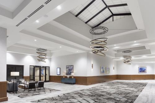 a rendering of the lobby of a building with tables and chairs at Crowne Plaza Lansing by IHG in Lansing
