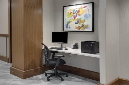 a desk with a computer and a chair in a room at Crowne Plaza Lansing by IHG in Lansing