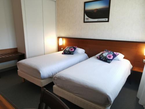 a hotel room with two beds and a tv on the wall at Logis Hôtel et Restaurant La Bombardière in Cuq-Toulza