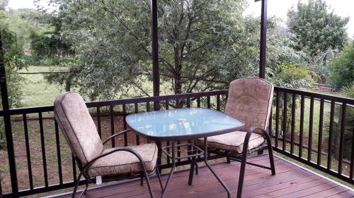 two chairs and a glass table on a deck at Stone Hill in Magaliesburg