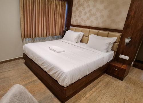 a bedroom with a large bed with a wooden headboard at Al Noor Palace in Bangalore