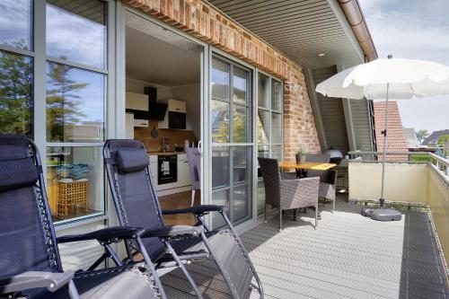 a porch with chairs and a table and an umbrella at Ostseerauschen in Zingst