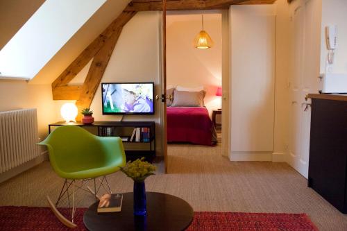 a living room with a green chair and a bedroom at Les Appartements d'Alexandre in Le Palais