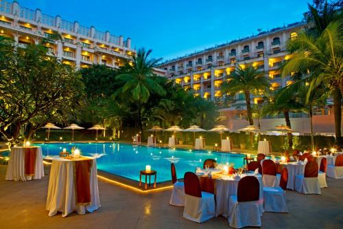 a hotel patio with tables and a pool at night at The Leela Palace Bengaluru in Bangalore