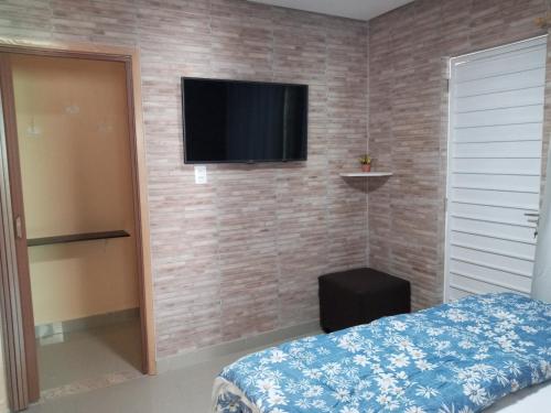 a bedroom with a television on a brick wall at Flat Recanto do Sertão in Piranhas