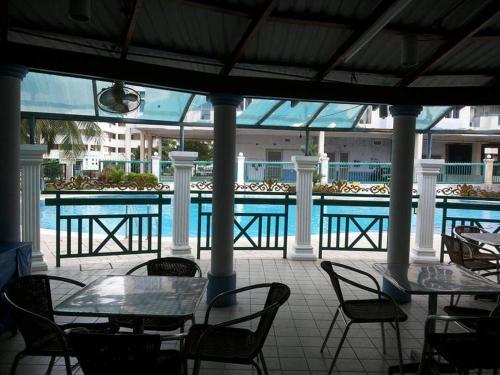 un patio con tavoli e sedie accanto alla piscina di SugarStay Homestay Teluk Kemang a Port Dickson