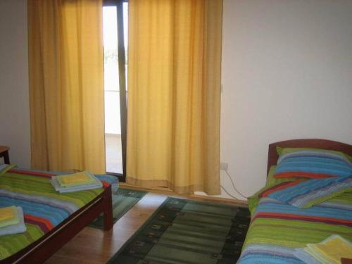 a room with two beds and a window with curtains at Bazeni Baikal in Topola