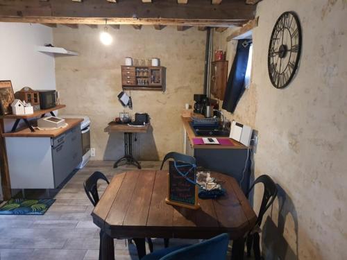 une cuisine avec une table en bois et une horloge au mur dans l'établissement Gîte du Moulin de Barutel Espace Spa Bien-être en supplément, à Mamers