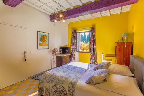 a bedroom with a bed with yellow walls and a window at REMY A DIT in Saint-Rémy-de-Provence