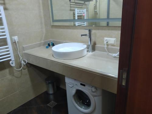 ein Badezimmer mit einem Waschbecken und einer Waschmaschine in der Unterkunft Sea View Apartment at Oasis Dreamland Resort in Chakvi