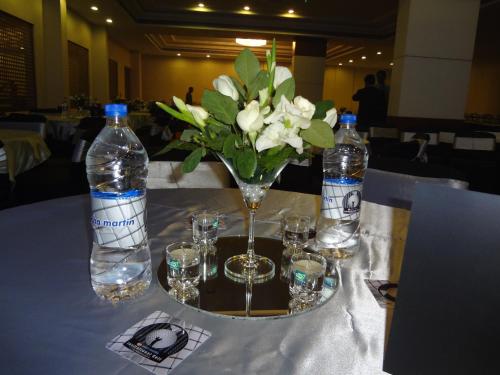 a table with a vase of flowers and water bottles at Ramada Jamshedpur Bistupur in Jamshedpur