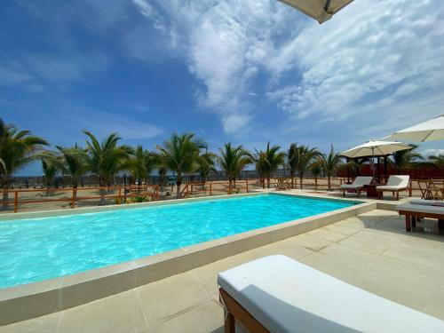 una piscina con palmeras en el fondo en El Samay Hotel Boutique en Canoas de Punta Sal