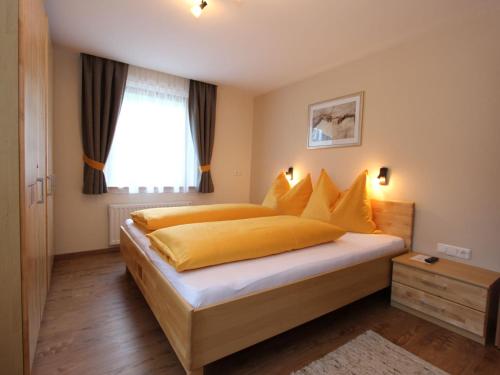 a bedroom with a bed with yellow sheets and a window at Spacious Apartment in Kleinarl near Ski Lift in Kleinarl