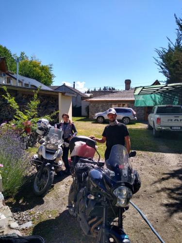 two men standing next to motorcycles parked in a yard at Hotel y Cabañas Casa de Piedra in Trevelin