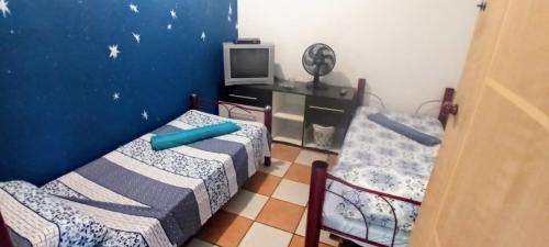a room with two beds and a tv in it at Morada BemTeVi Guest House in São José dos Campos