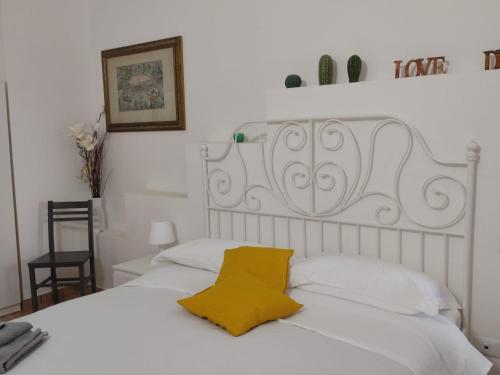 a white bed with a yellow pillow on it at Le casette di Frà al Bondì in Santa Severa