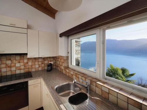 a kitchen with a sink and a large window at Avalon in Brissago