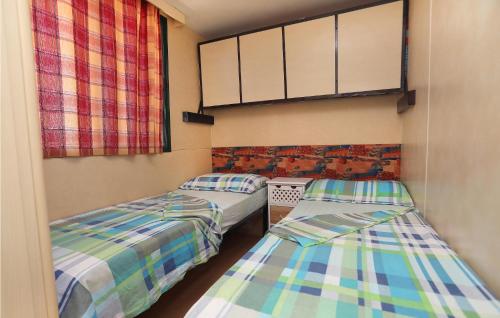 two twin beds in a room with two windows at Amazing stacaravan In Trogir With Kitchen in Trogir