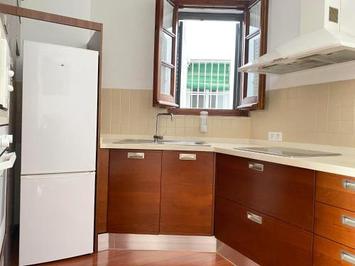 uma cozinha com armários de madeira e um frigorífico branco em Hispalis San Julian em Sevilha