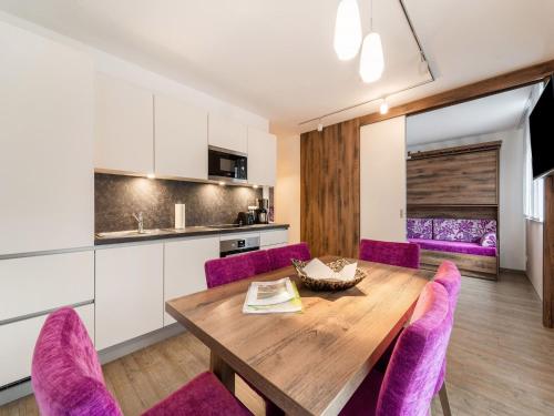 una cucina e una sala da pranzo con tavolo in legno e sedie viola di Modern apartment in St Georgen near Salzburg a Fürstau