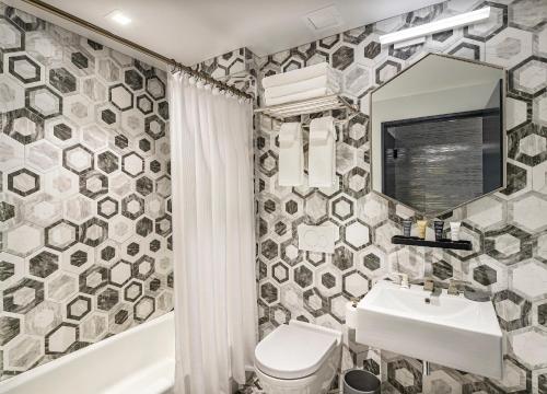 a bathroom with a sink and a toilet and a mirror at The FIDI Hotel in New York