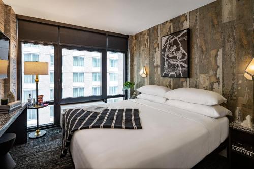 a bedroom with a large white bed and a large window at The FIDI Hotel in New York